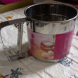 Easy-to-use manual flour sifter with a shaker mechanism, ideal for precise and lump-free baking.